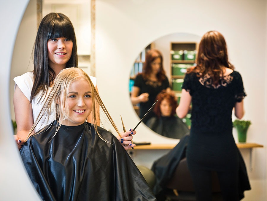 Salon worker cutting womens wet hair